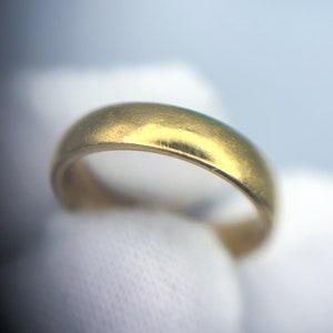 May include: A simple gold wedding band with a smooth, polished finish.