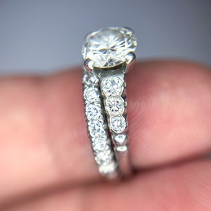 May include: A silver engagement ring set with a large round center diamond and a band of smaller diamonds.