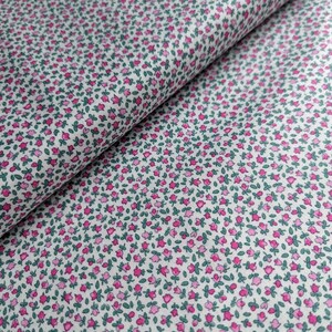 Pode incluir: Tecido branco com uma pequena estampa floral rosa e verde. O tecido est&aacute; dobrado ao meio, mostrando o padr&atilde;o em ambos os lados.