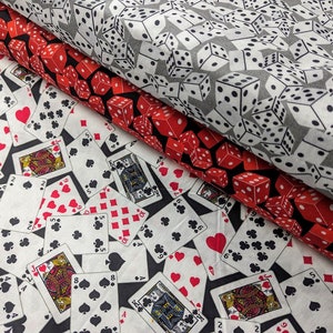 Puede incluir: Dos muestras de tela con fondo negro y fondo blanco. La tela negra tiene un patrón de cartas de juego con diferentes palos y números. La tela blanca tiene un patrón de dados blancos con puntos negros.