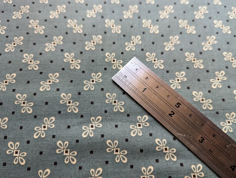 Pode incluir: Close-up de um tecido azul com um padr&atilde;o floral branco. Uma r&eacute;gua &eacute; colocada sobre o tecido, mostrando a escala em cent&iacute;metros.