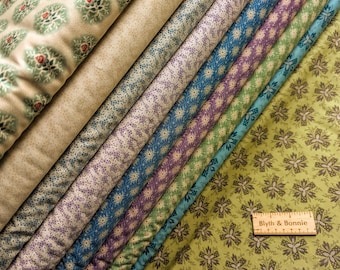 Pode incluir: Uma coleção de oito amostras de tecido com diferentes padrões florais. Os tecidos são em tons de verde, azul, roxo e branco. As amostras são dispostas em forma de leque, com a amostra inferior sendo de cor verde sólida com um padrão floral. Uma régua com o texto "Blyth & Bonnie" é colocada em cima das amostras.
