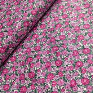Pode incluir: Tecido floral rosa e roxo com fundo branco. O tecido &eacute; coberto por pequenas flores com folhas verdes.