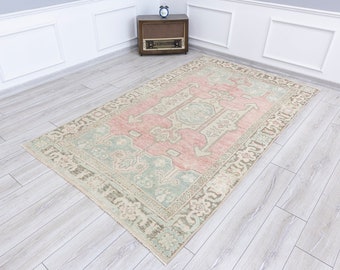 Puede incluir: Una alfombra vintage con una combinación de colores rosa claro, beige y verde. La alfombra tiene un diseño tradicional con un medallón central y motivos florales.