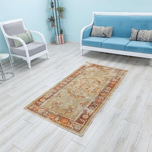 Puede incluir: Una alfombra vintage con fondo beige y un patr&oacute;n floral en tonos naranja, rojo y marr&oacute;n. La alfombra est&aacute; colocada sobre un suelo de madera clara en una habitaci&oacute;n con muebles blancos.