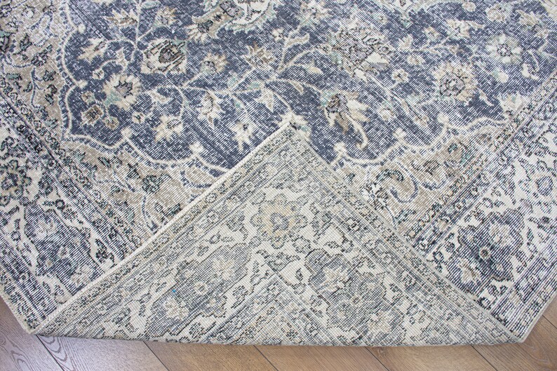 May include: Close-up of a corner of a blue and cream patterned rug with a floral design. The rug has a distressed, vintage look.