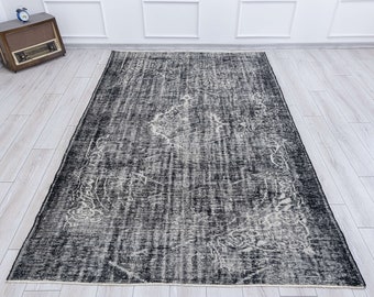 May include: A black and white vintage rug with a faded floral pattern. The rug has a distressed look and is made of a soft, woven material.