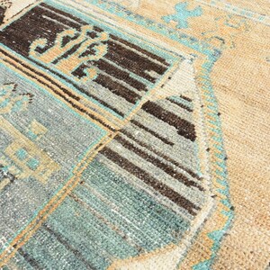 May include: A vintage rug with a geometric pattern in shades of blue, brown, and beige. The rug has a distressed look and is woven with a variety of textures.