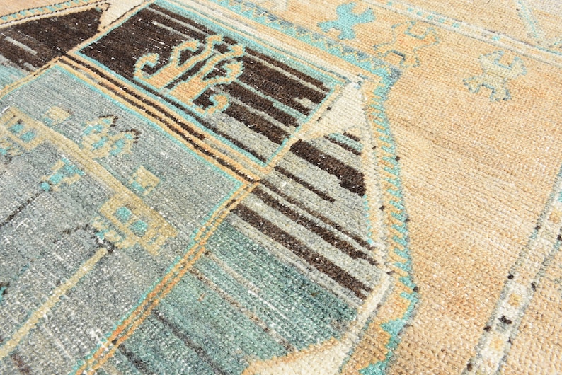 May include: A vintage rug with a geometric pattern in shades of blue, brown, and beige. The rug has a distressed look and is woven with a variety of textures.