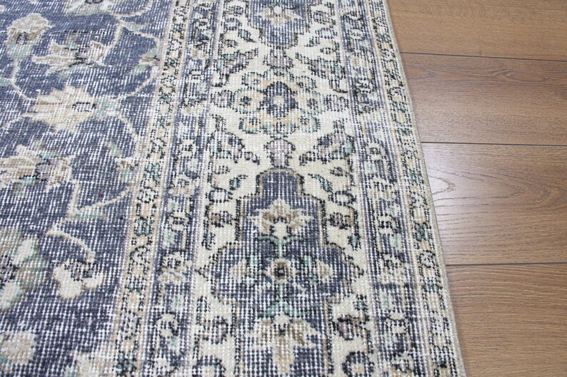 May include: A vintage rug with a cream and blue floral pattern. The rug has a distressed look and is made of a woven material.