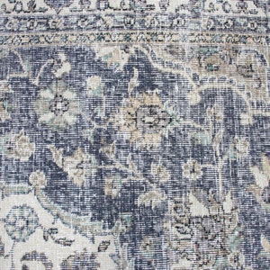 May include: A vintage rug with a blue and white floral pattern. The rug has a distressed look and is made of a woven material.