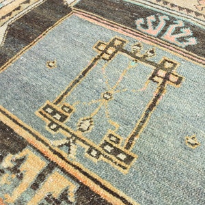 May include: A close-up of a blue and brown rug with a geometric pattern. The rug has a light blue center with a brown border and a geometric design in the center.