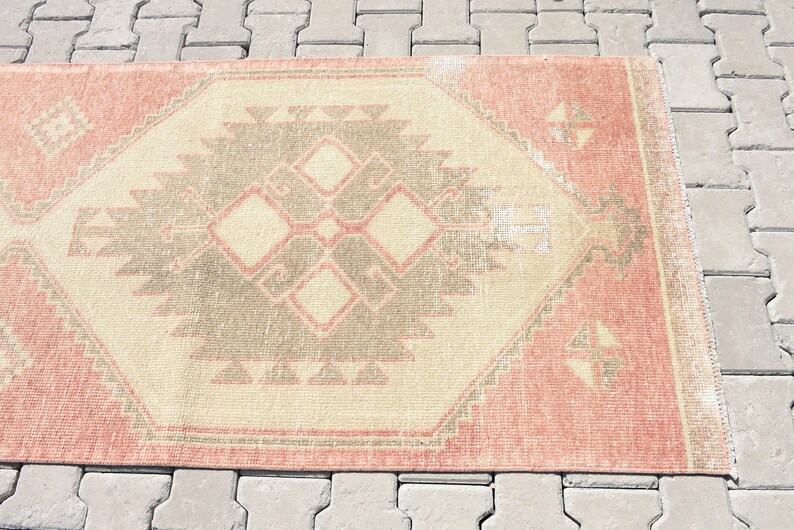 Puede incluir: Una alfombra vintage con un patr&oacute;n geom&eacute;trico en tonos rosa, beige y gris. La alfombra tiene un aspecto desgastado y es perfecta para a&ntilde;adir un toque de estilo bohemio a cualquier habitaci&oacute;n.