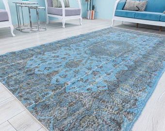 Puede incluir: Una alfombra vintage de color azul y gris con un patrón desgastado y descolorido. La alfombra tiene un diseño floral y es perfecta para añadir un toque de estilo bohemio a cualquier habitación.