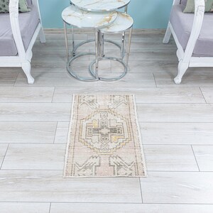May include: A light beige runner rug with a geometric pattern in shades of brown, yellow, and pink. The rug is placed on a light wood floor in front of a set of three nesting tables with chrome legs.