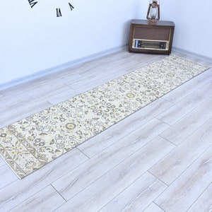 Puede incluir: Un tapete de pasillo beige y amarillo con un diseño floral. El tapete está colocado sobre un suelo de madera claro.