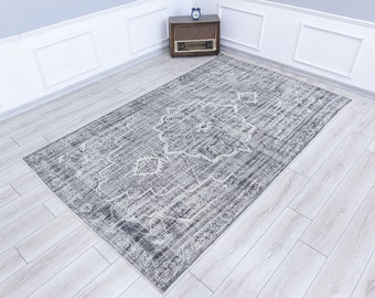 May include: A gray and white patterned rug with a distressed look. The rug has a floral design and is laid out on a light wood floor.