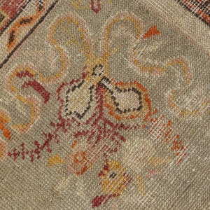 Puede incluir: Primer plano de una alfombra beige con intrincados patrones en tonos rojos, naranjas y marrones. La alfombra tiene un aspecto desgastado y vintage.
