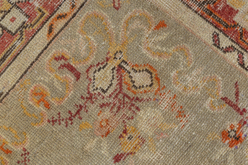 Puede incluir: Primer plano de una alfombra beige con intrincados patrones en tonos rojos, naranjas y marrones. La alfombra tiene un aspecto desgastado y vintage.