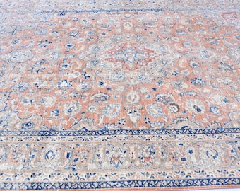 May include: A vintage rug with a floral pattern in shades of pink, blue, and white. The rug has a detailed border with a repeating pattern.