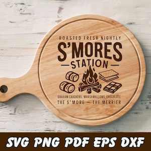 May include: A round wooden cutting board with a handle, engraved with "S'MORES STATION" and illustrations of marshmallows, graham crackers, chocolate, and a campfire. The text "Roasted Fresh Nightly" and "The S' More - The Merrier" are also included.