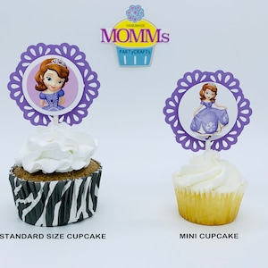 Puede incluir: Toppers de cupcake morados con un personaje de princesa con un vestido morado. Los toppers se muestran en un cupcake de tamaño estándar con un forro de estampado de cebra y un mini cupcake.