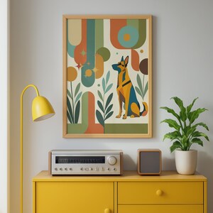 May include: A framed wall art print featuring a stylized German Shepherd dog sitting amidst abstract geometric shapes, curved lines, and leaf motifs in a palette of muted orange, teal, olive green, and cream, displayed in a light wood frame.