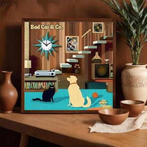 May include: A framed artwork featuring a mid-century modern interior scene with a black cat and a yellow dog. The artwork includes a starburst clock, a record player, and the text "Bad Cat & Co."