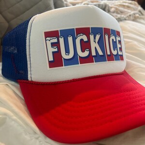 May include: A red, white, and blue trucker hat with the text "FUCK ICE" in white block letters. The hat has a red brim, a white front panel, and a blue mesh back.