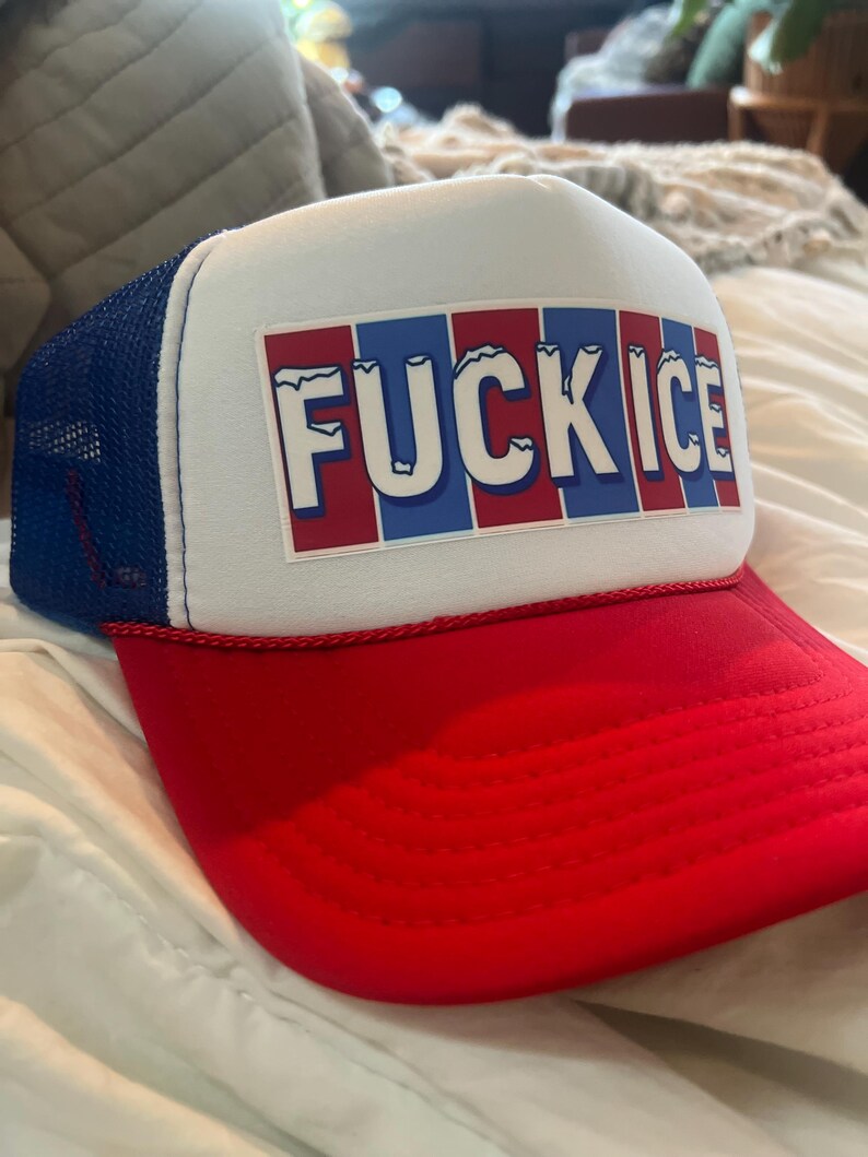 May include: A red, white, and blue trucker hat with the text "FUCK ICE" in white block letters. The hat has a red brim, a white front panel, and a blue mesh back.