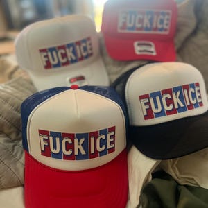 May include: Four baseball caps with the text "FUCK ICE" in red, white, and blue block letters. The caps are white, red, black, and blue. The caps have a mesh back and a curved brim.