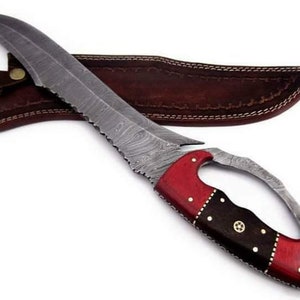 May include: A Damascus steel knife with a red and black wood handle. The knife has a curved blade and a leather sheath.