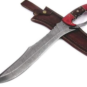 May include: A large, curved, Damascus steel knife with a red and brown wood handle. The knife has a leather sheath with stitching.