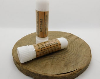 May include: Two white roll-on essential oil blend tubes on a wooden surface. The tubes are labelled "Uplifting Essential Oil Blend" and "Stress Essential Oil Blend".