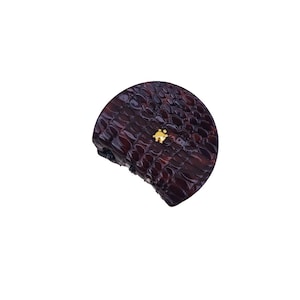 Può includere: Una pochette marrone scuro, a forma di semicerchio, con un motivo strutturato simile a quello di un rettile. Un piccolo elemento decorativo color oro è fissato sulla parte anteriore. La pochette è su sfondo bianco.