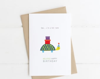 May include: A white card with a green, yellow, and blue turtle carrying a stack of gifts. The text on the card reads "Ops...I'm a bit late" and "Belated Happy Birthday".
