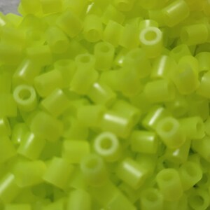 May include: A large pile of bright yellow plastic beads. The beads are small and cylindrical with a hole in the center.