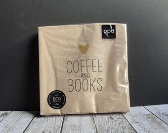 May include: A package of brown paper napkins with the words "COFFEE AND BOOKS" printed in black. A gold heart is above the text. The napkins are labeled "ECO EDITION" and are on a wooden surface.