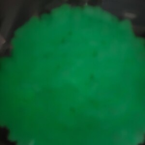 May include: A close-up of a bright green, smooth, round object. The object is slightly blurred.