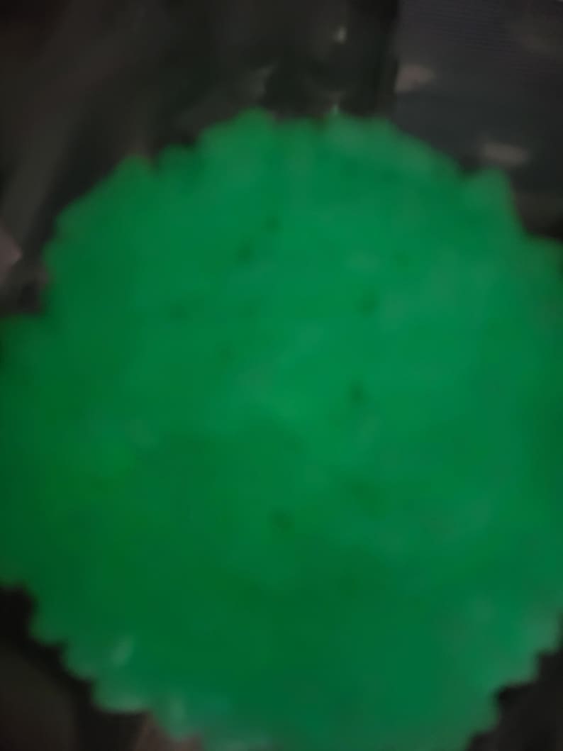 May include: A close-up of a bright green, smooth, round object. The object is slightly blurred.