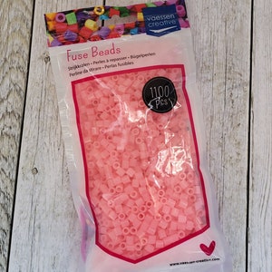 May include: A bag of 1100 pink fuse beads, also known as ironing beads, for crafting. The bag is labeled "Fuse Beads" and has the brand name "vaessen creative" printed on it.