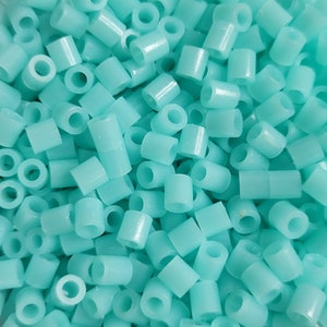 May include: A close-up of a pile of turquoise plastic beads. The beads are small and cylindrical, with a hole in the center. They are perfect for crafting projects.