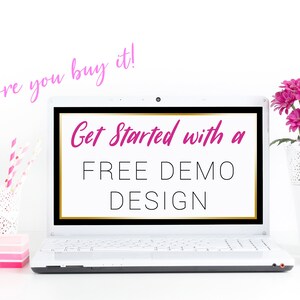 May include: A white laptop computer with a black screen displaying the text "Get Started with a FREE DEMO DESIGN". The text "Try it before you buy it!" is written in pink above the laptop. The laptop is on a white surface with a pink stapler, a white vase with pink and white flowers, and a white mug.