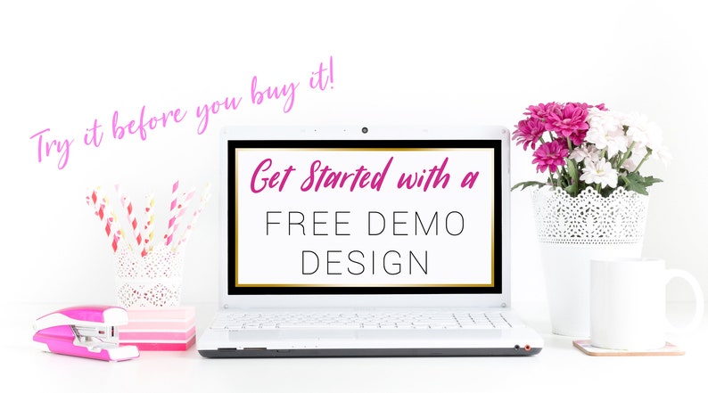 May include: A white laptop computer with a black screen displaying the text "Get Started with a FREE DEMO DESIGN". The text "Try it before you buy it!" is written in pink above the laptop. The laptop is on a white surface with a pink stapler, a white vase with pink and white flowers, and a white mug.