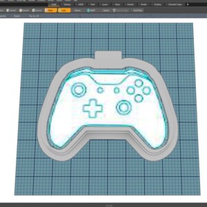 Może przedstawiać: Trójwymiarowy model białego kontrolera do gier wideo z niebieskim obramowaniem. Kontroler został zaprojektowany tak, aby przypominał popularny kontroler do konsoli do gier.