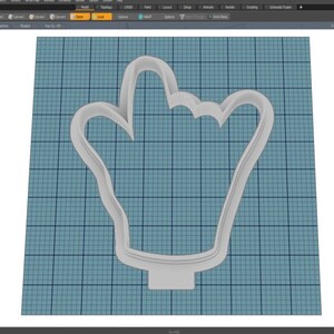 May include: A white plastic cookie cutter shaped like a hand with the index finger pointing up.