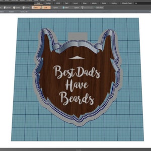 May include: A blue and white cookie cutter in the shape of a beard with the text "Best Dads Have Beards" on a wood grain background.