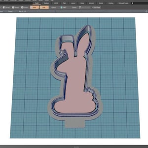 May include: A 3D model of a cookie cutter in the shape of a bunny rabbit. The cutter is made of blue plastic and is shown on a blue grid background.