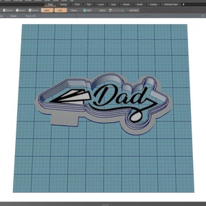 May include: A 3D model of a cookie cutter in the shape of the word "Dad" with a paper airplane on the left side. The cookie cutter is made of silver metal and is shown on a blue grid background.