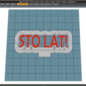 May include: A white plastic cookie cutter in the shape of a banner with the words "STO LAT!" in red letters.